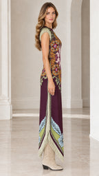 Side profile view of woman modeling plum floral print maxi dress showing side slit and fringe shoulder detail