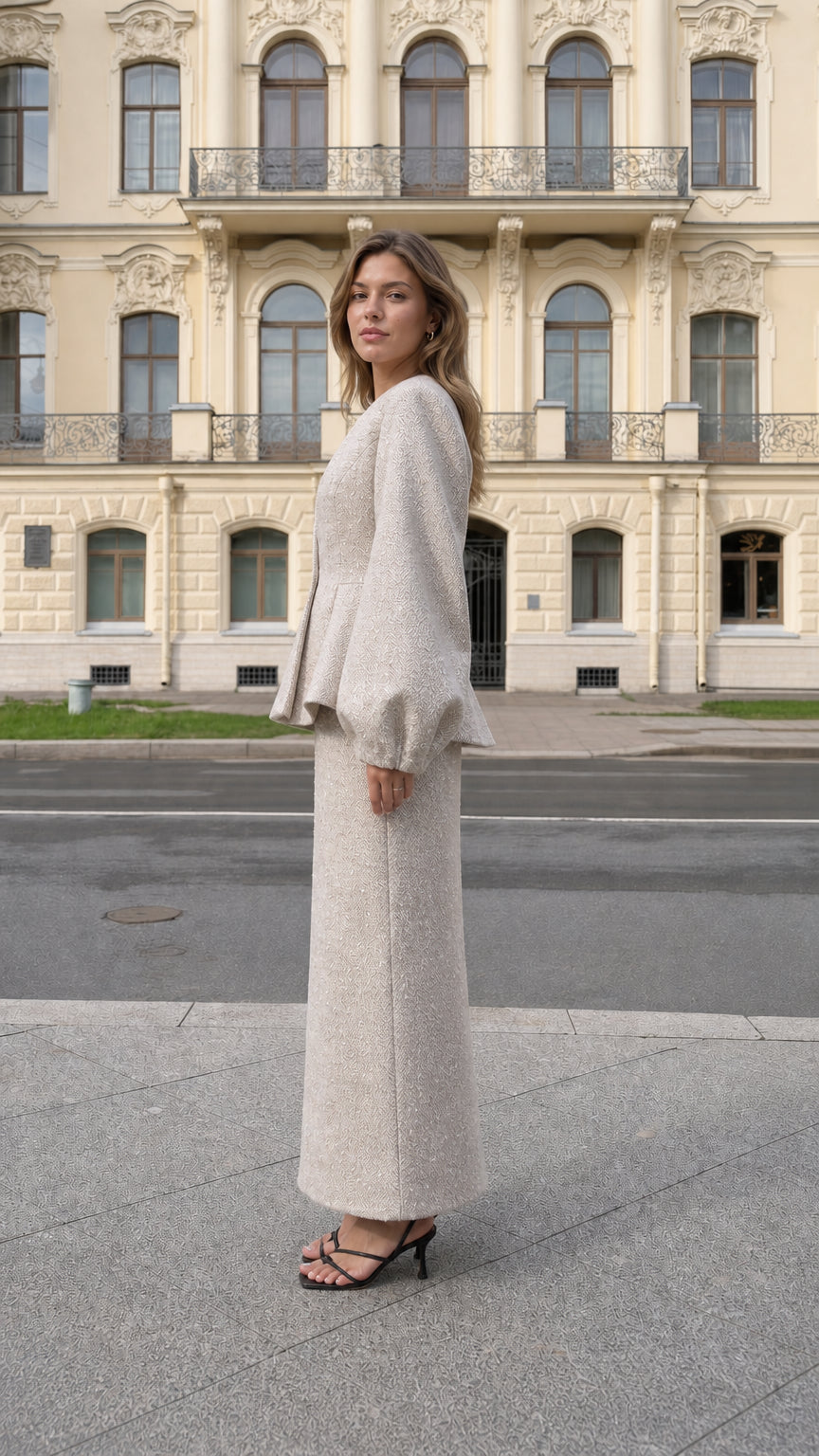 Side profile view of beige tweed peplum jacket and long skirt set