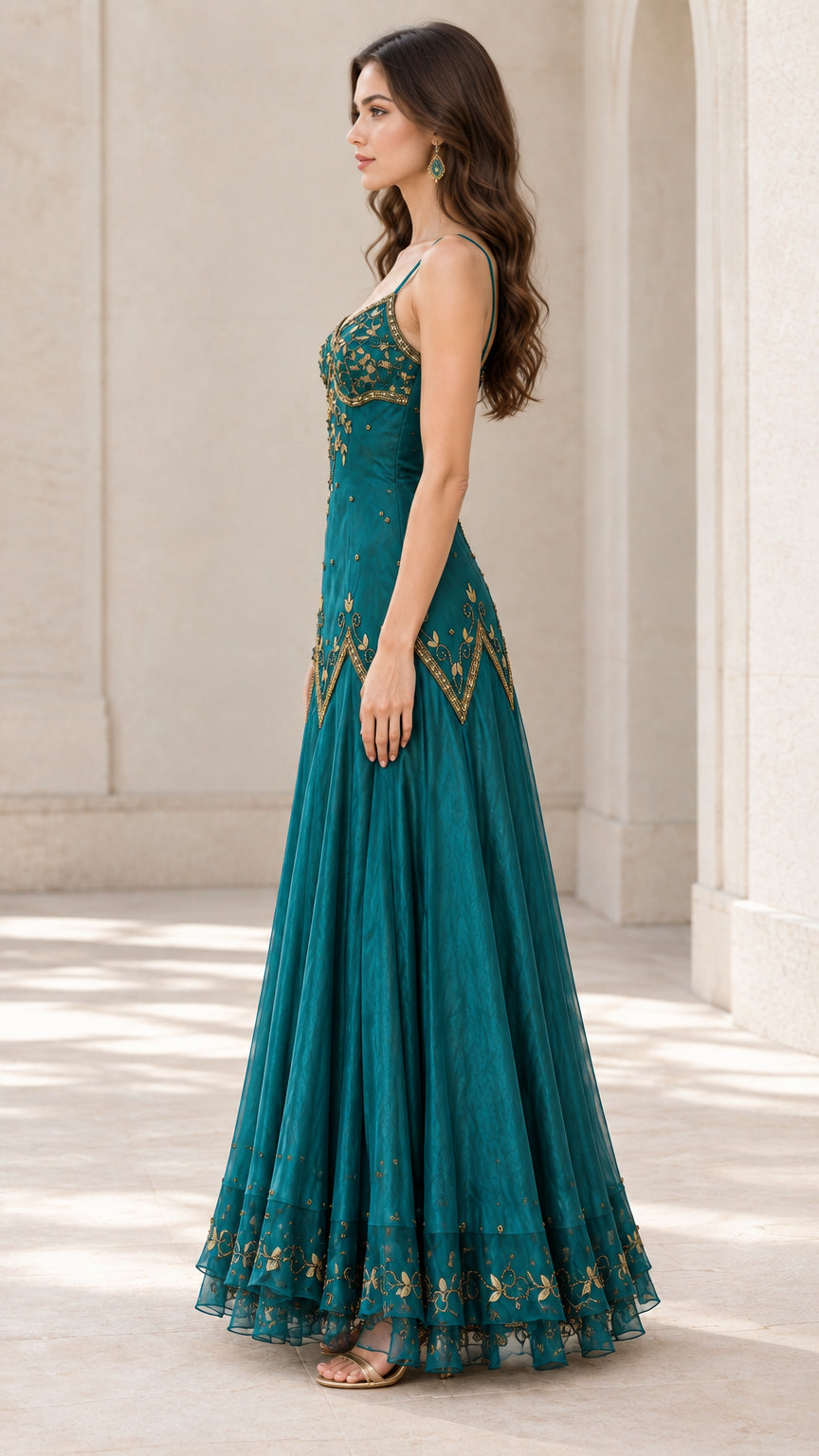 Side profile of woman in teal sleeveless embroidered maxi gown