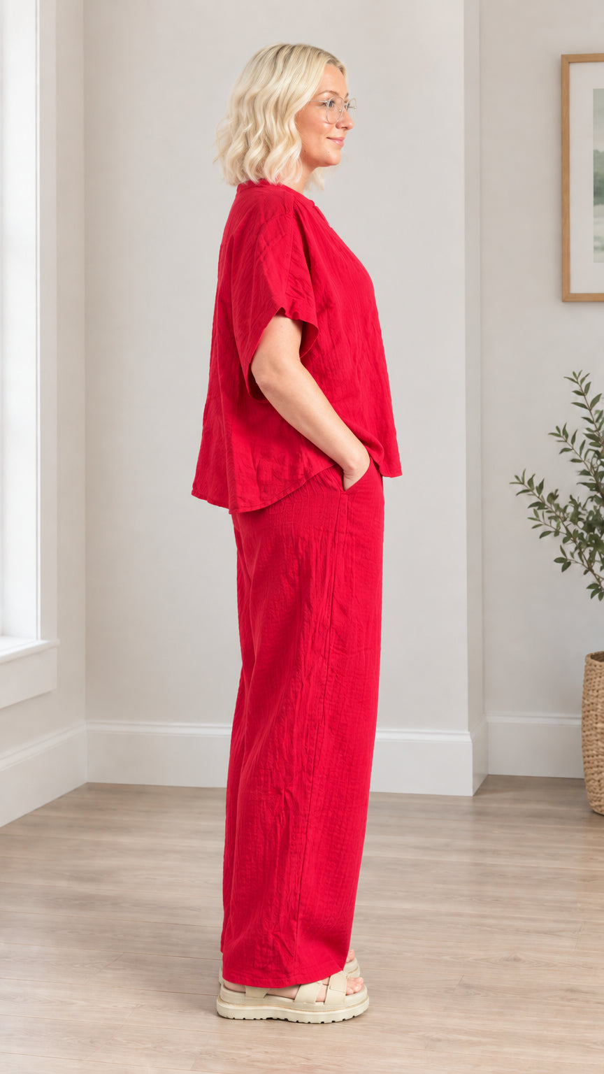 Side profile view of model wearing red two-piece matching lounge set with hands in pockets