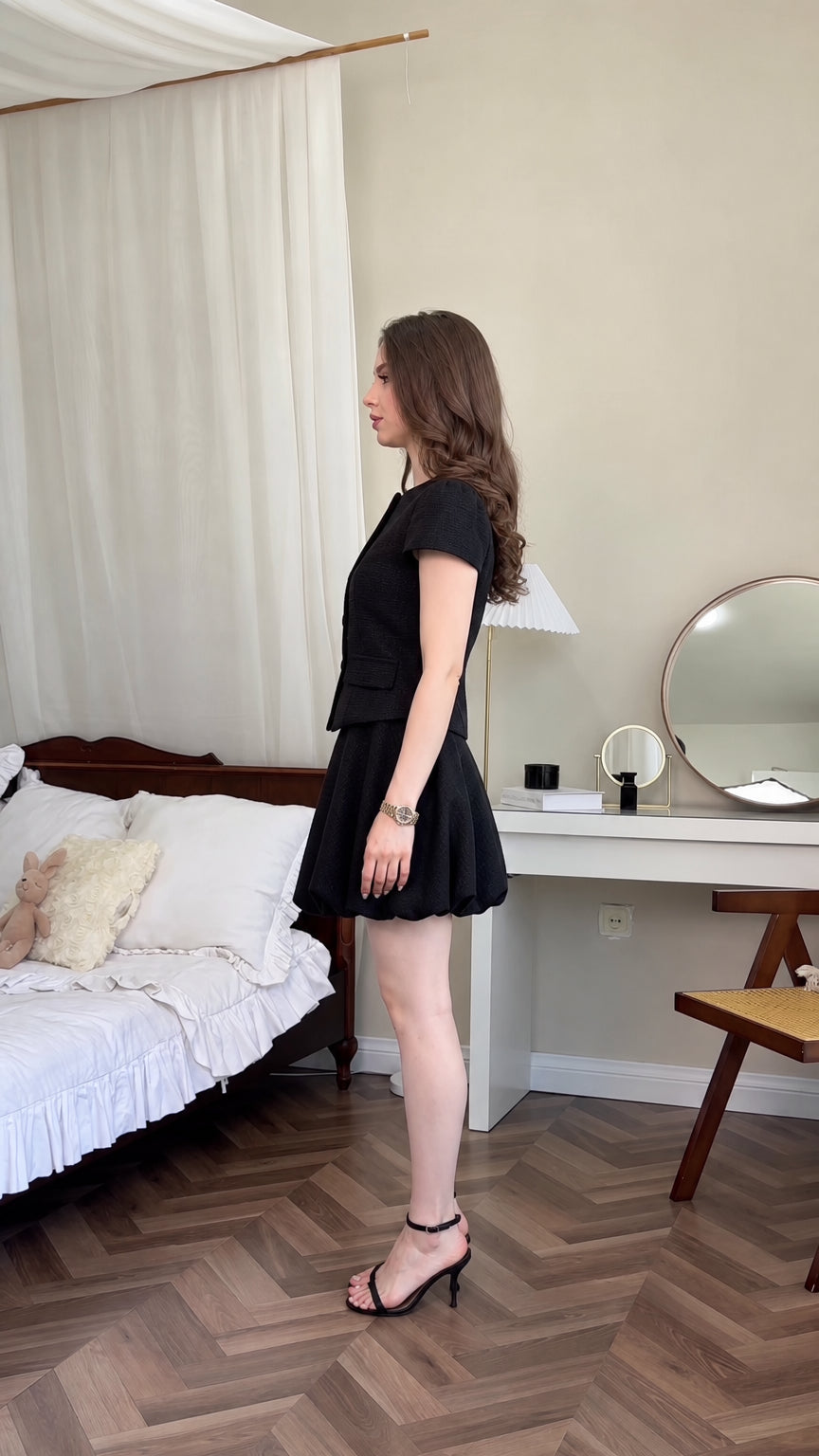 Side profile of model wearing black tweed matching skirt set