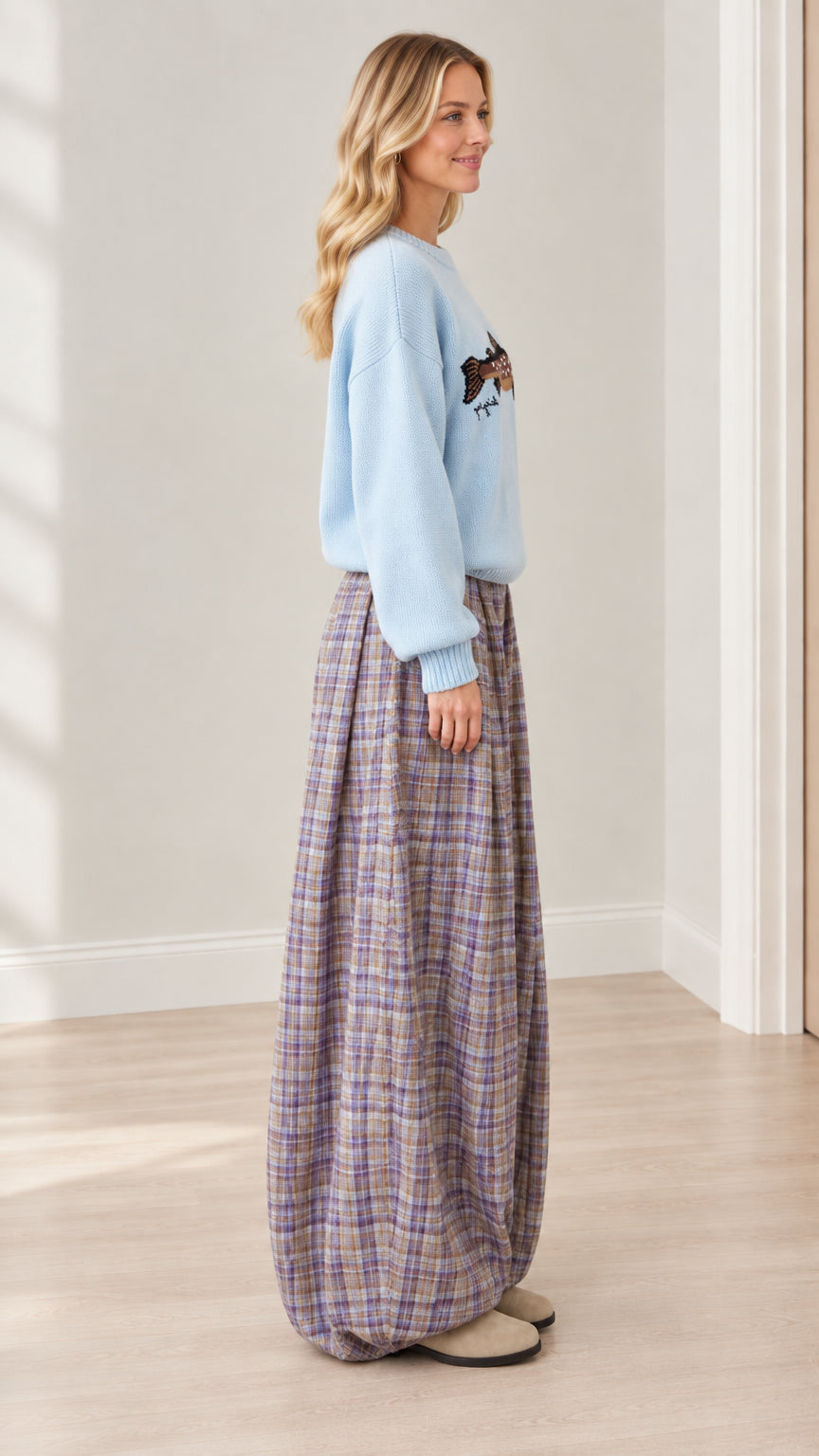 Side profile view of model wearing light blue graphic knit top and wide-leg plaid trousers