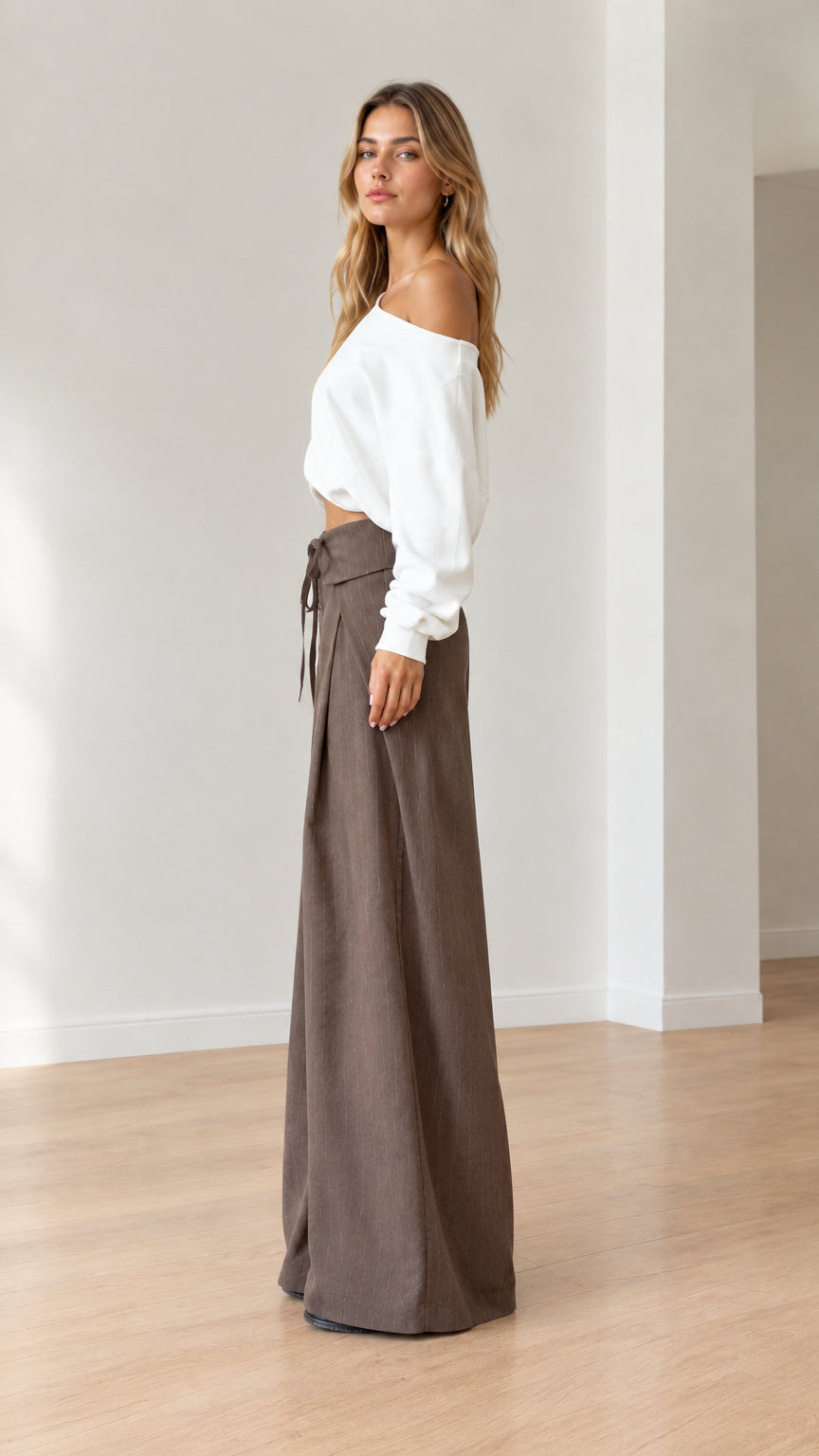 Side profile of model wearing wide-leg brown trousers with fold-over waist