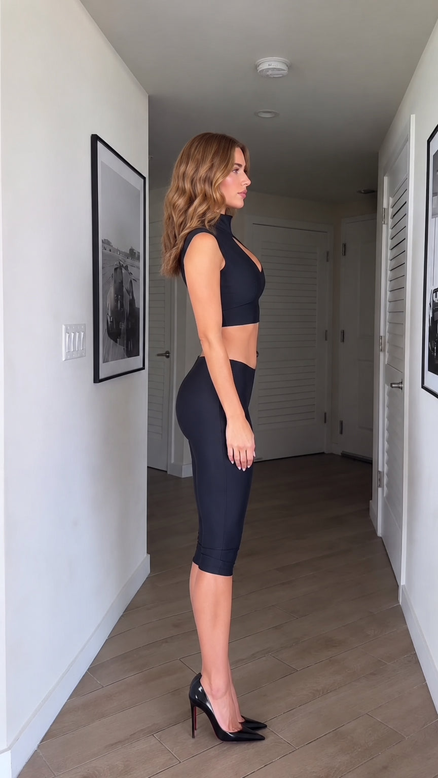 Side profile view of model wearing black crop top and knee-length leggings set