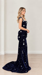 Side profile view of navy blue embellished velvet gown showing the cascading hip sash drape and train