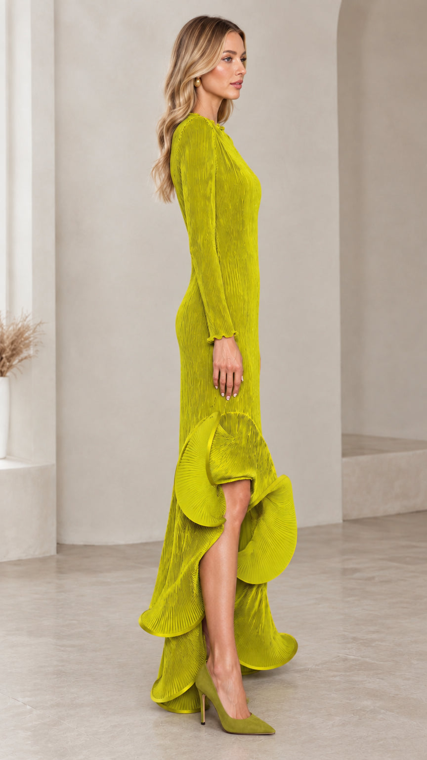 Side profile of model wearing the chartreuse long sleeve plisse gown showing the sculpted cascade hemline