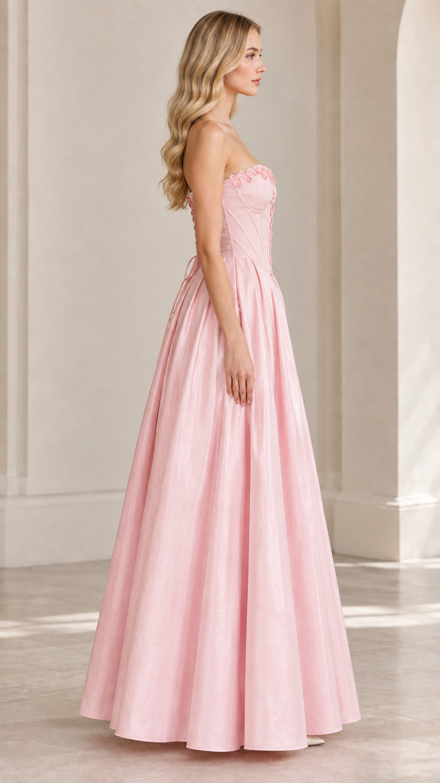 Side profile view of model in light pink strapless lace-up ball gown