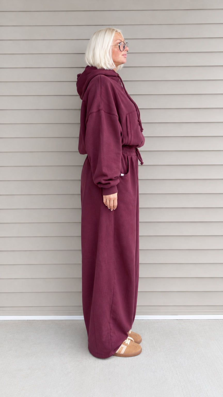 Side profile view of woman wearing burgundy 2-piece hoodie and sweatpants set