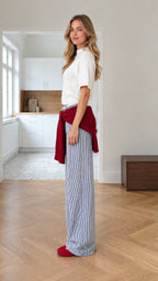 Side profile view of woman wearing white knit top and striped wide-leg pants