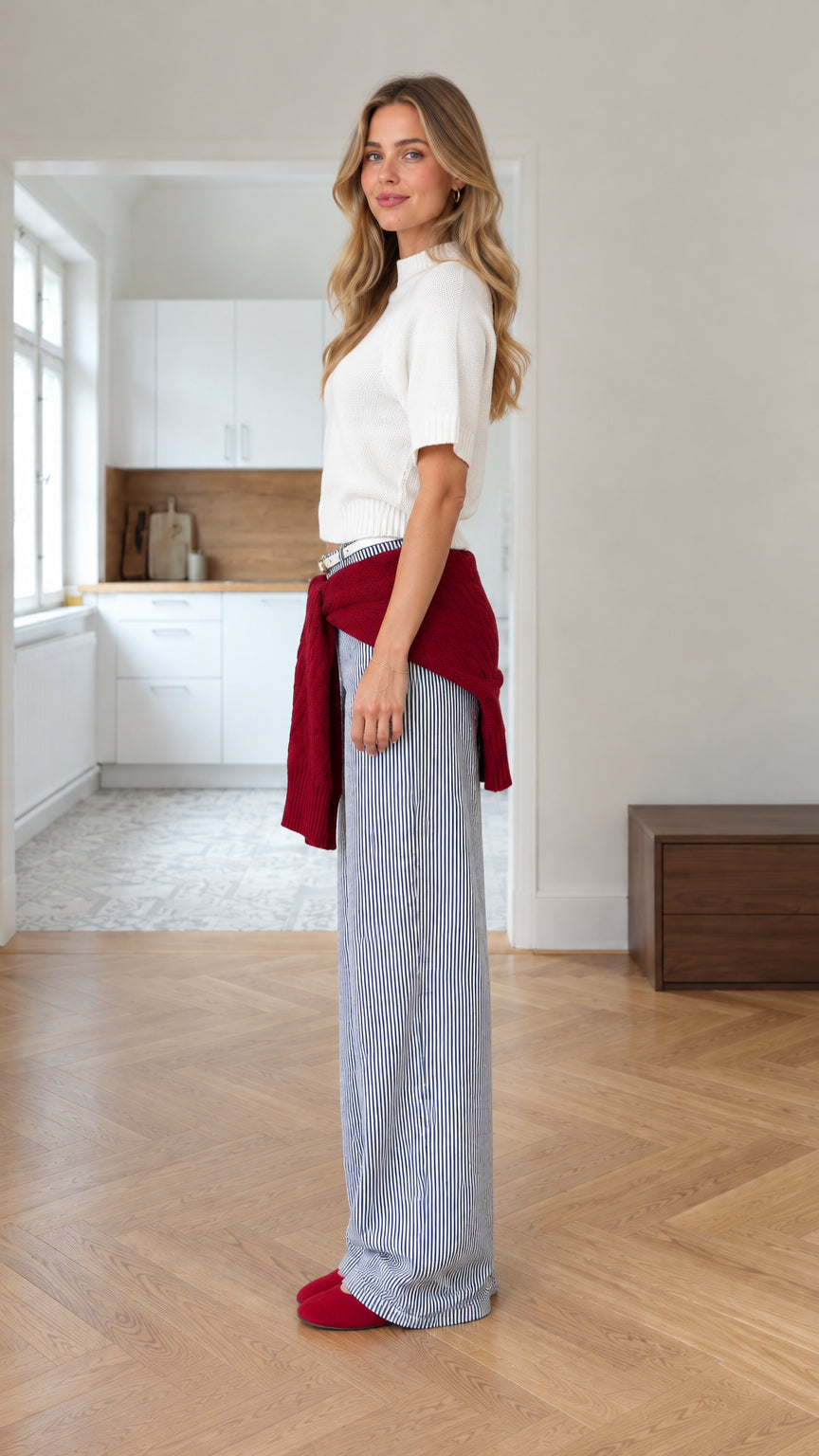 Side profile view of woman wearing white knit top and striped wide-leg pants