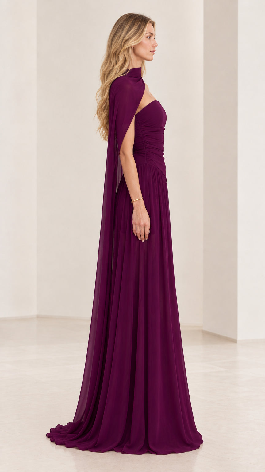 Side profile of woman wearing plum ruched chiffon formal gown with draped capelet