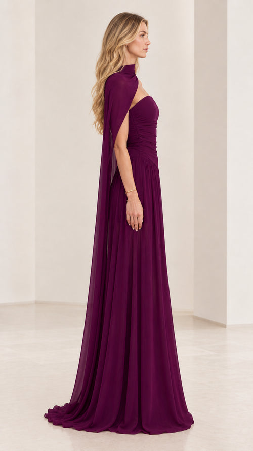 Side profile of woman wearing plum ruched chiffon formal gown with draped capelet