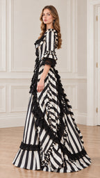 Side profile of woman in full-length black and white striped Victorian gown showing ruffled skirt layers