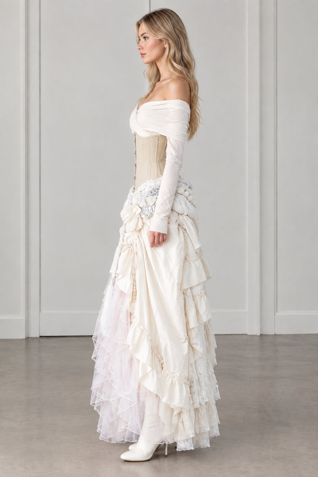 Side profile of model wearing ivory off-shoulder corset tiered gown