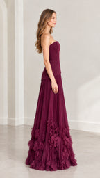 Side profile of model wearing burgundy strapless pleated evening gown