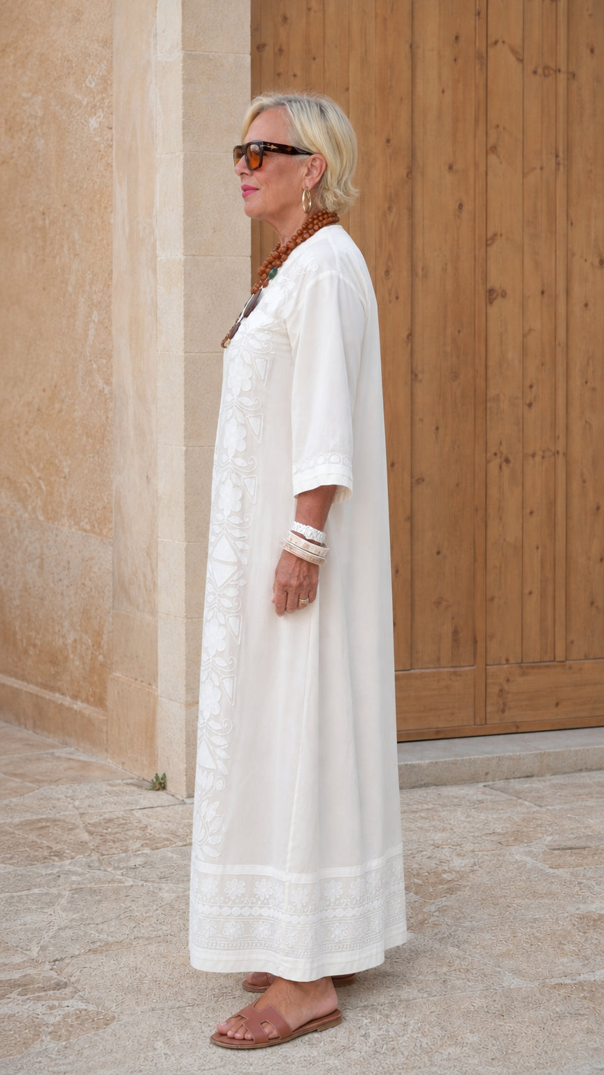 Side view of woman in white embroidered kaftan maxi dress