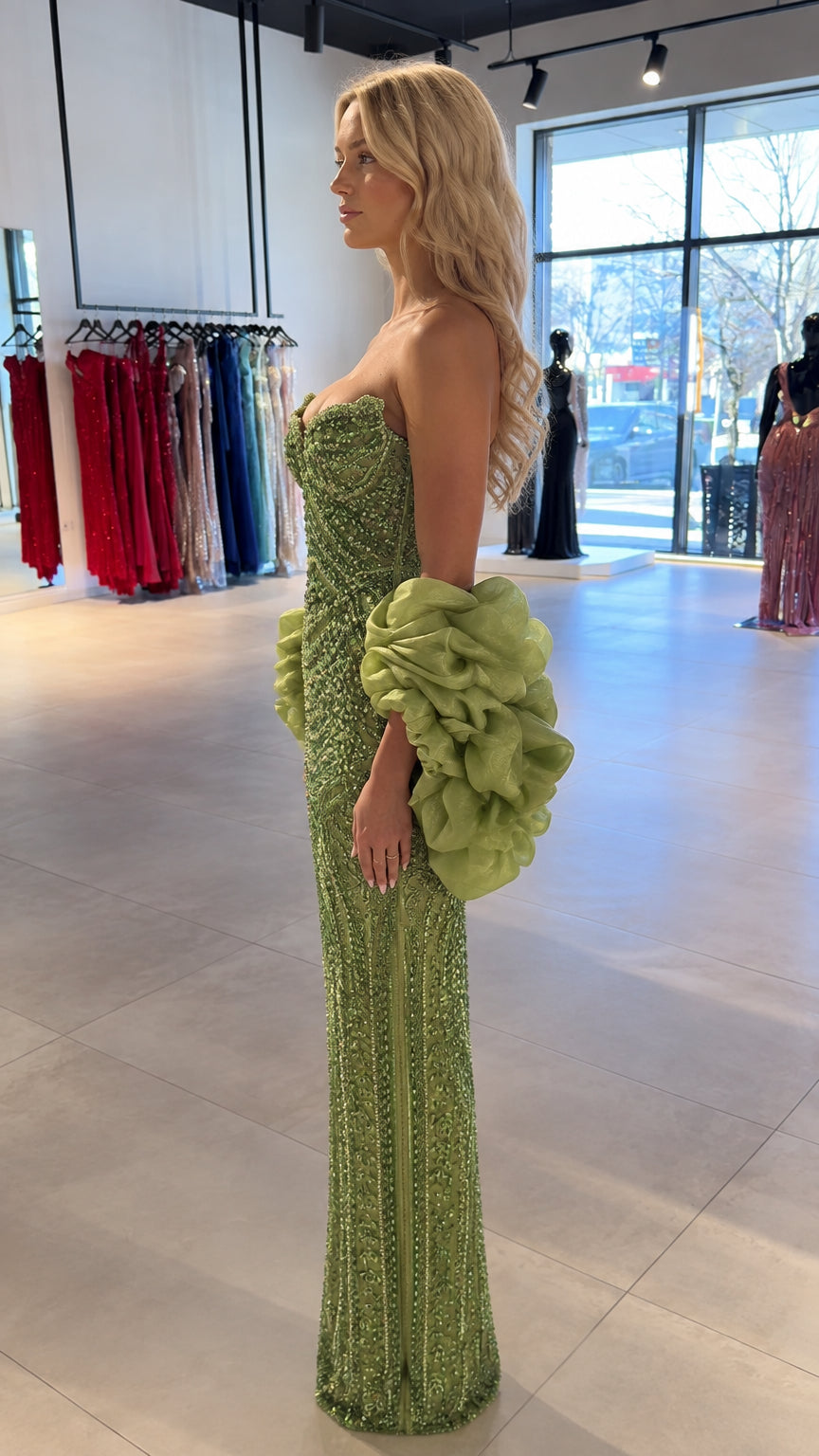 Side profile of model wearing green beaded strapless evening dress with ruffled arm accents