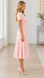 Side profile view of model wearing blush pink tweed flared midi dress