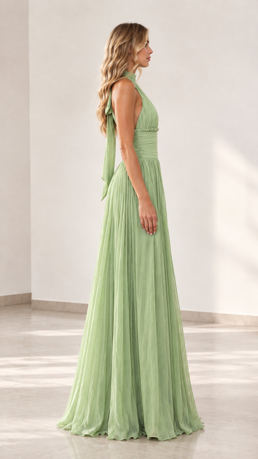 Side profile view of woman wearing sage green pleated halter gown