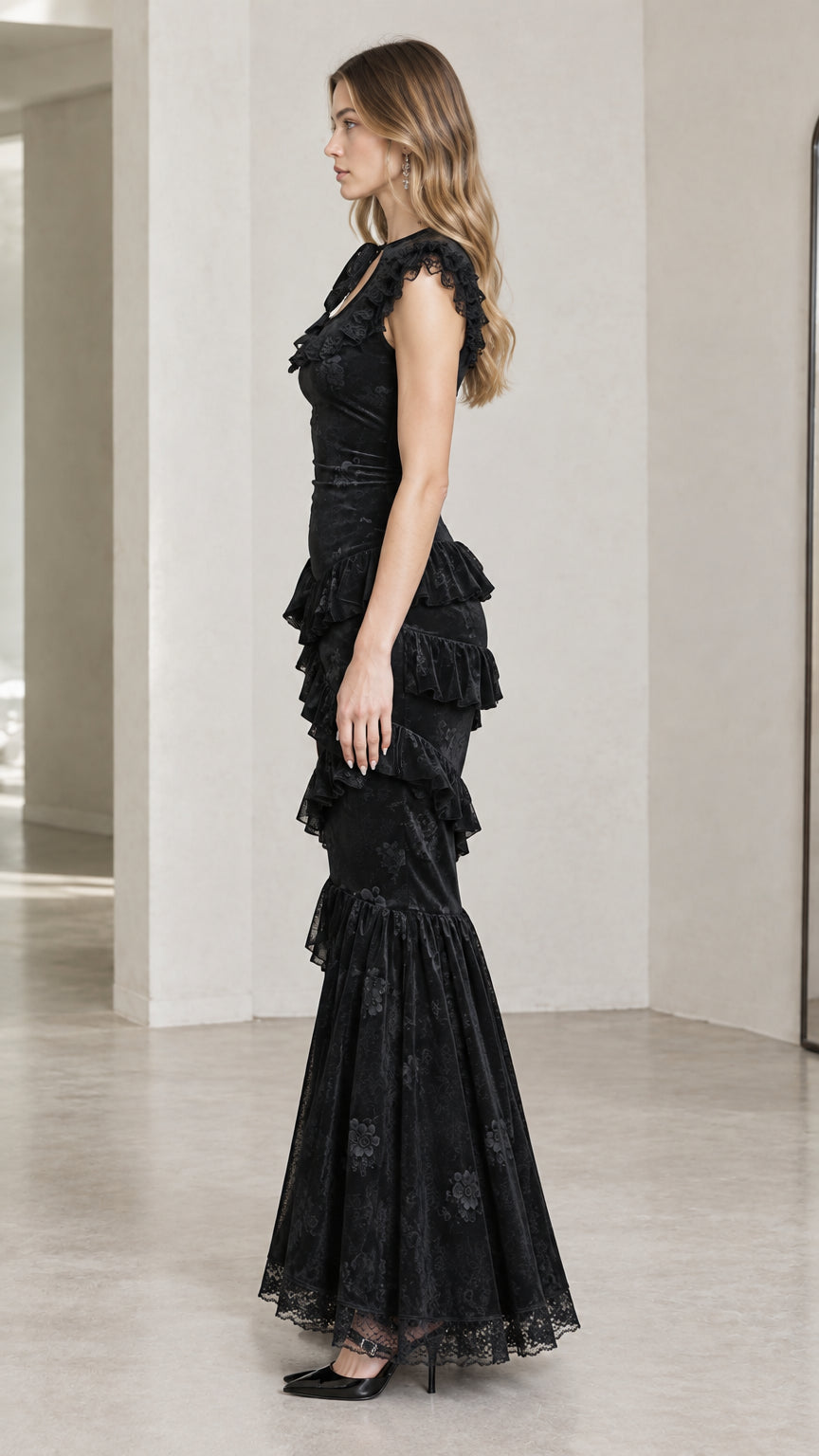 Side profile view of model wearing black floral jacquard maxi dress with cascading ruffles