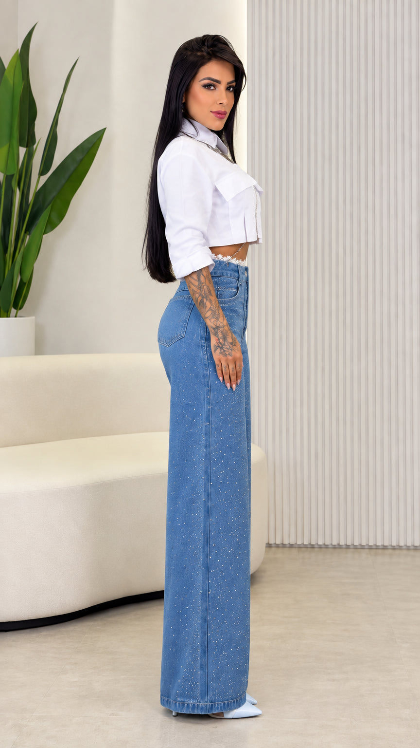 Side profile view showing the long wide leg drape of blue rhinestone pants with cropped top