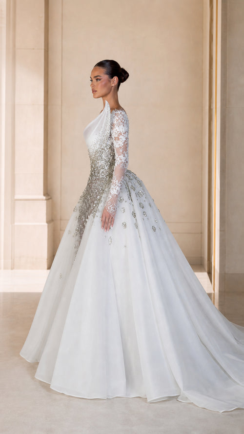 Side profile of white embellished long sleeve formal dress with voluminous train