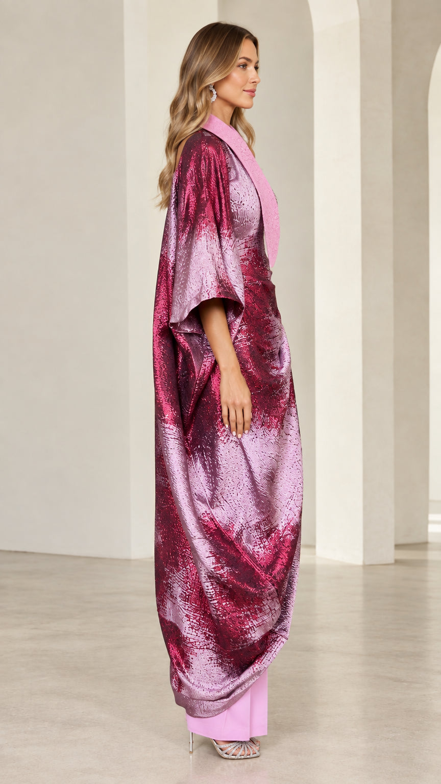 Side profile view of model in fuchsia pink shimmer kaftan and trouser outfit