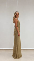 Side profile of model wearing floor-length gold glitter halter maxi dress