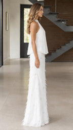 Side profile of white halter pleated maxi dress with feather embellishments