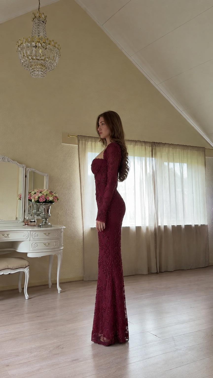Side profile of woman in burgundy long sleeve sweetheart formal maxi dress