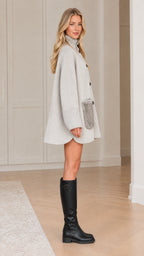 Side profile view of model in light grey oversized button-front cape coat