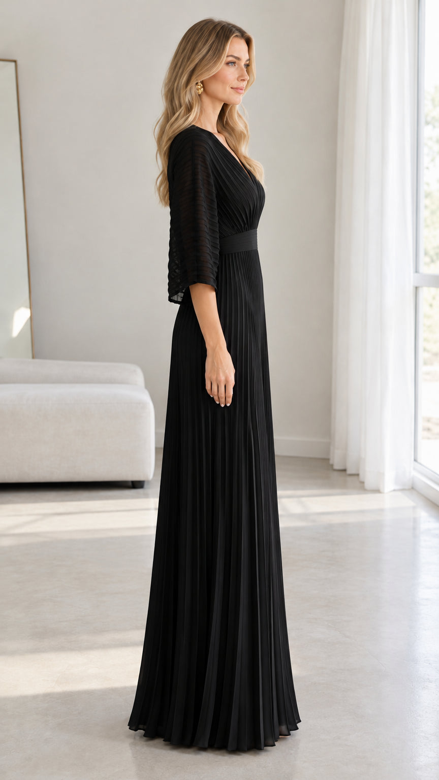 Side profile of model in a floor-length black pleated evening dress