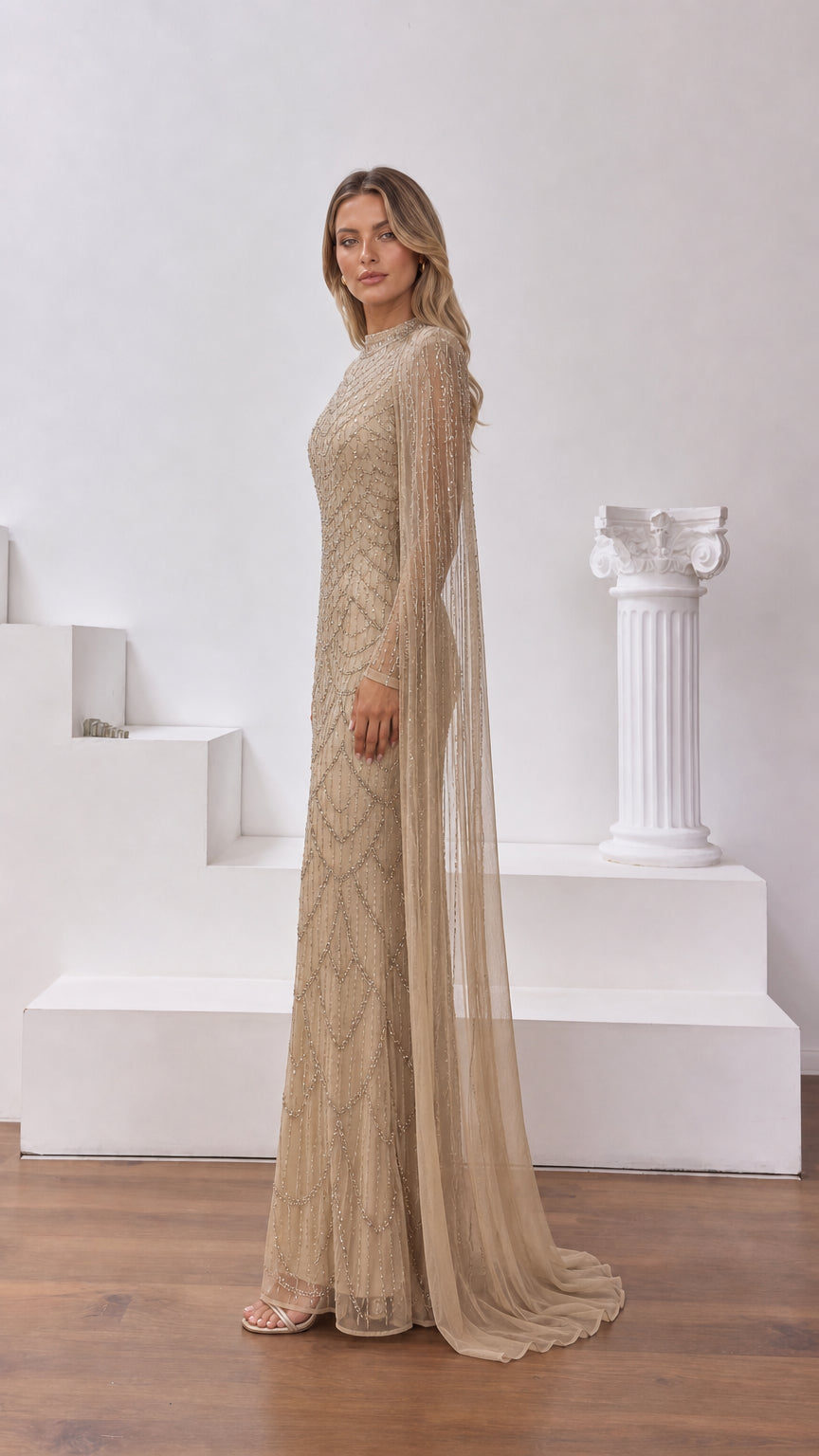 Side profile view of champagne beaded formal gown showing dramatic cape sleeve drape