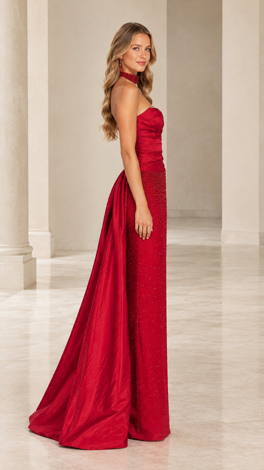 Side angle of model showcasing the silhouette of the red strapless gown with overskirt