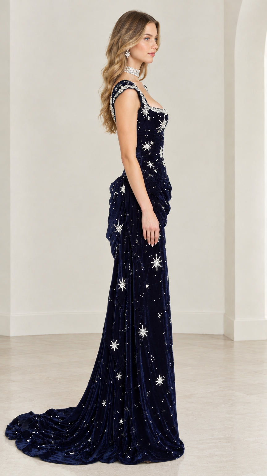 Side profile of model showing draped hip and sweeping train on midnight blue velvet evening gown