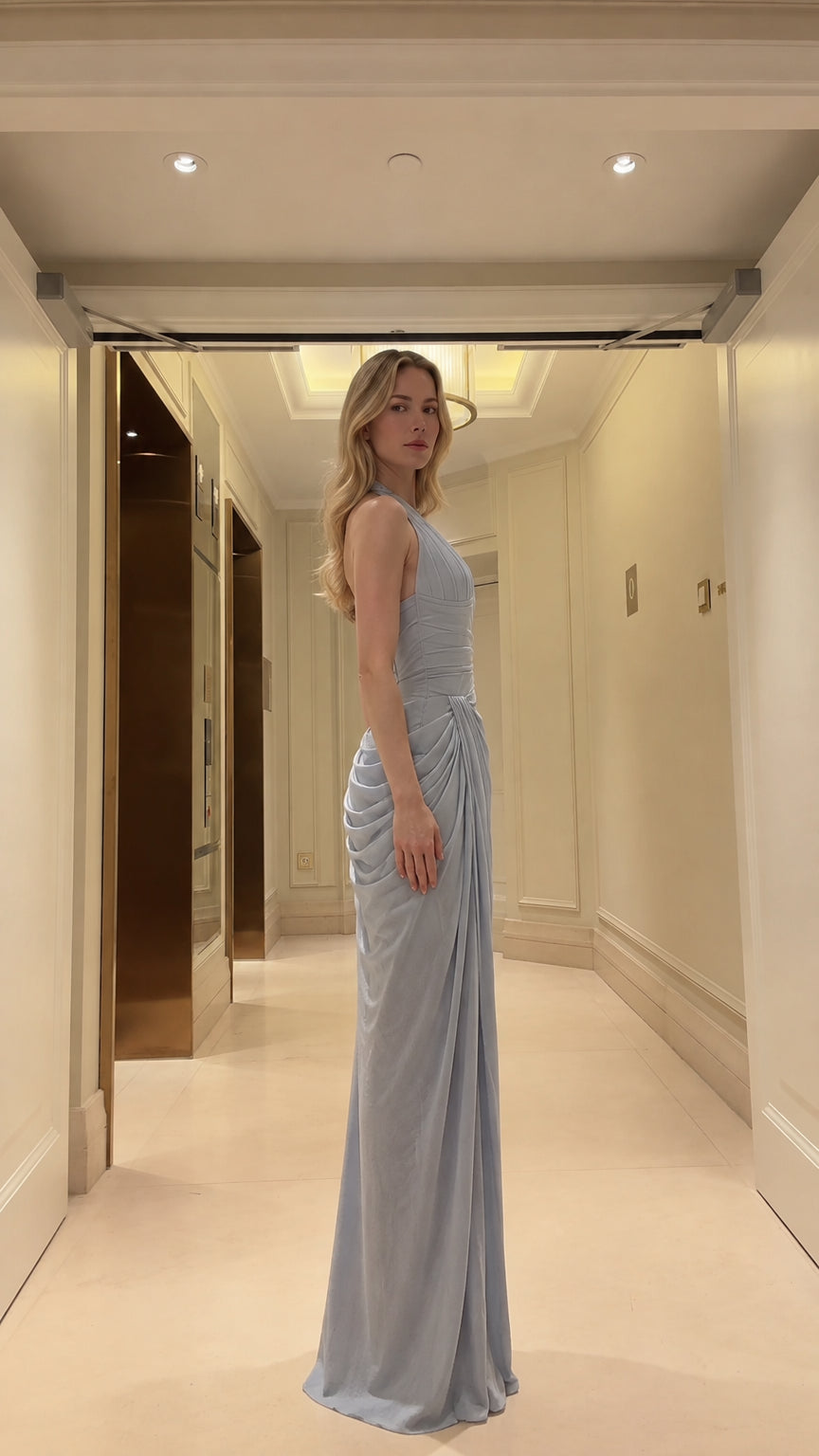 Side profile view of woman wearing dusty blue draped formal gown
