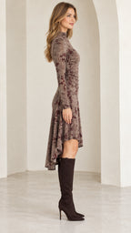 Side profile of model wearing mocha brown floral long sleeve dress with ruched waist and high-low hem