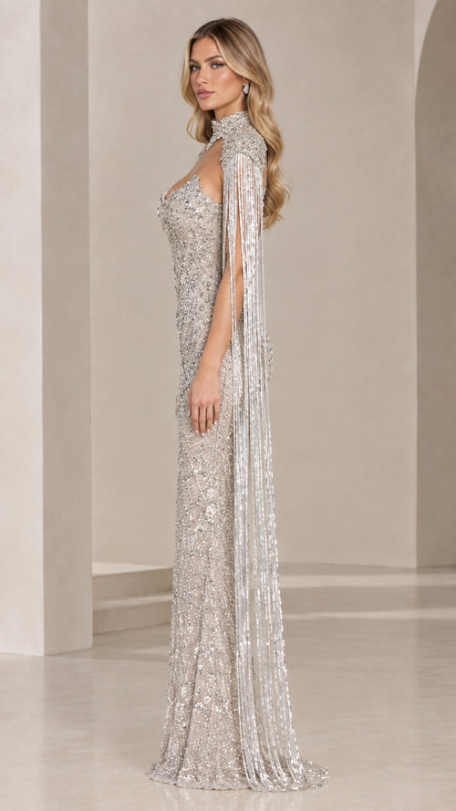 Side profile view of silver beaded gown showcasing the floor-sweeping beaded fringe cape sleeves