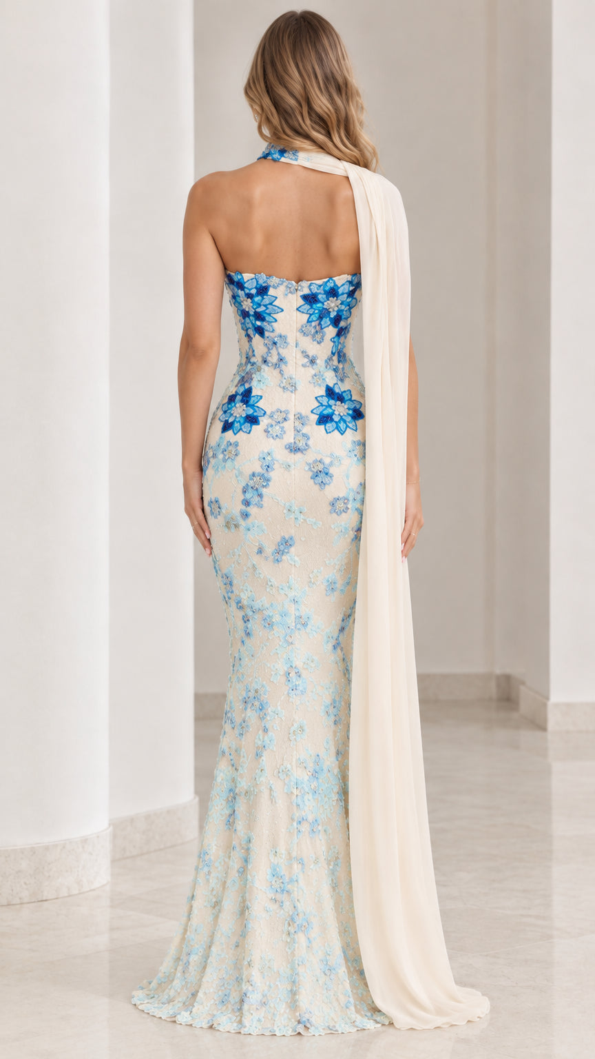 Back view of ivory strapless evening dress with blue floral accents and flowing cape drape