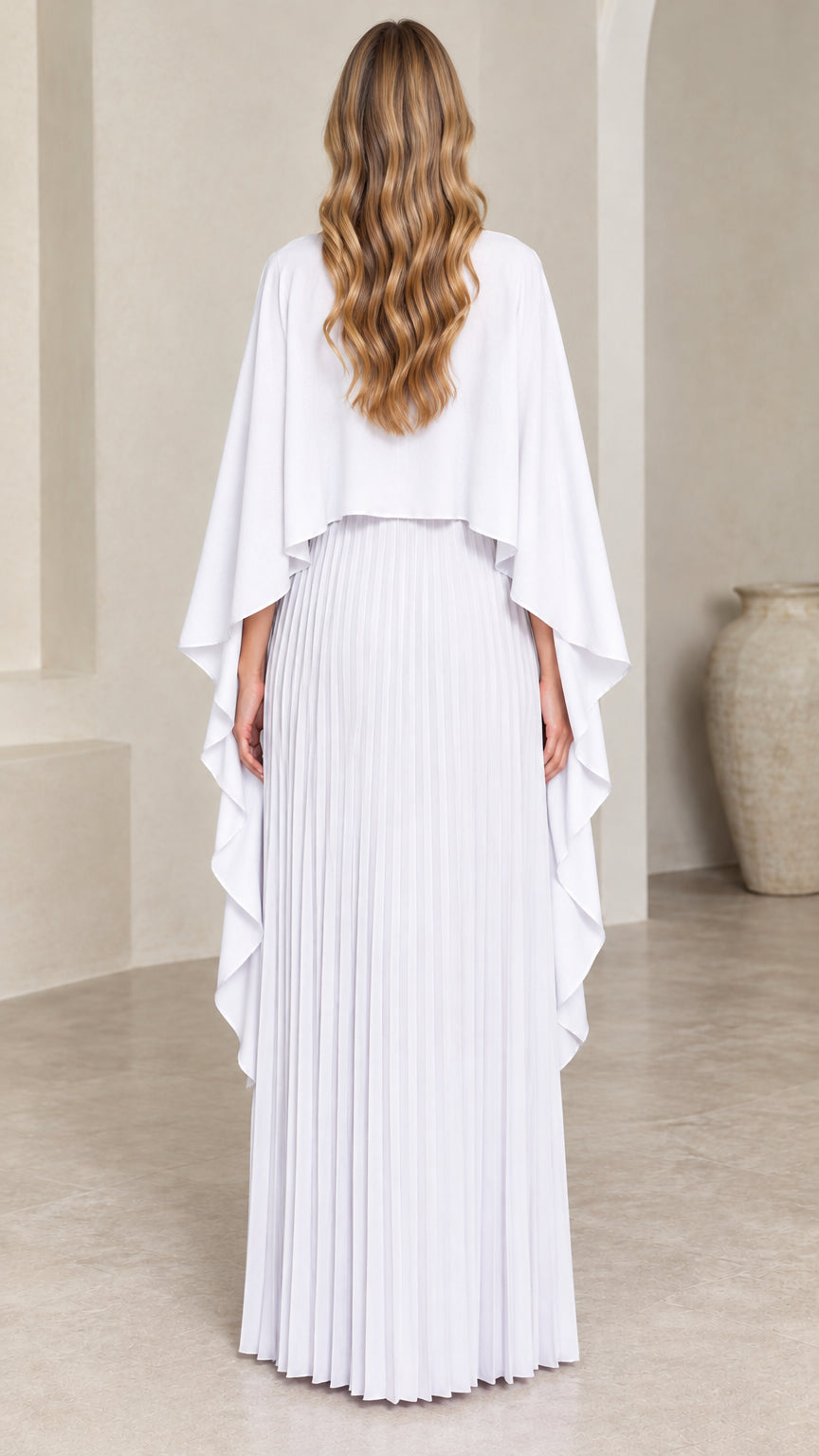 Back view of woman wearing white pleated cape maxi dress with draped overlay