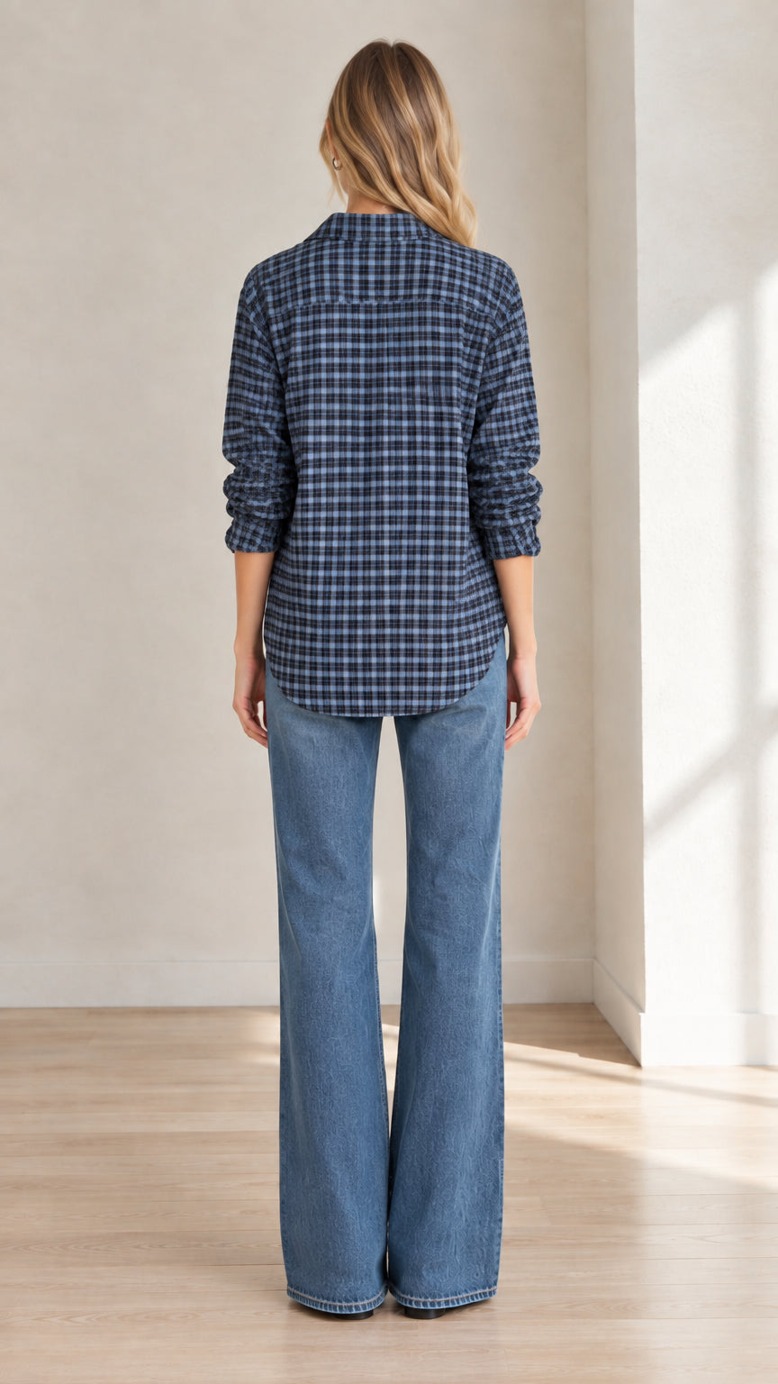 Rear view of model wearing blue plaid popover shirt with back yoke pleat