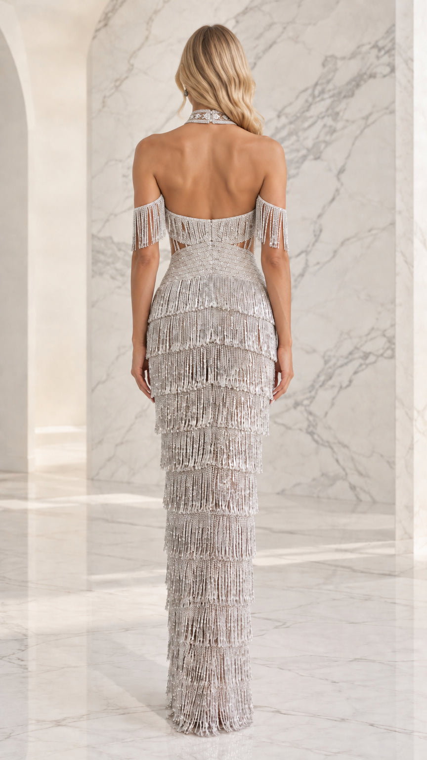 Back view of woman wearing silver beaded halter dress featuring an open back and fringe detailing