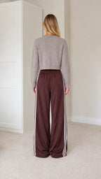 Rear view of model wearing grey knit cardigan and brown wide leg track pants