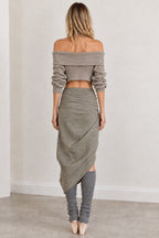 Back view of woman wearing sage green off-shoulder cropped sweater and draped skirt
