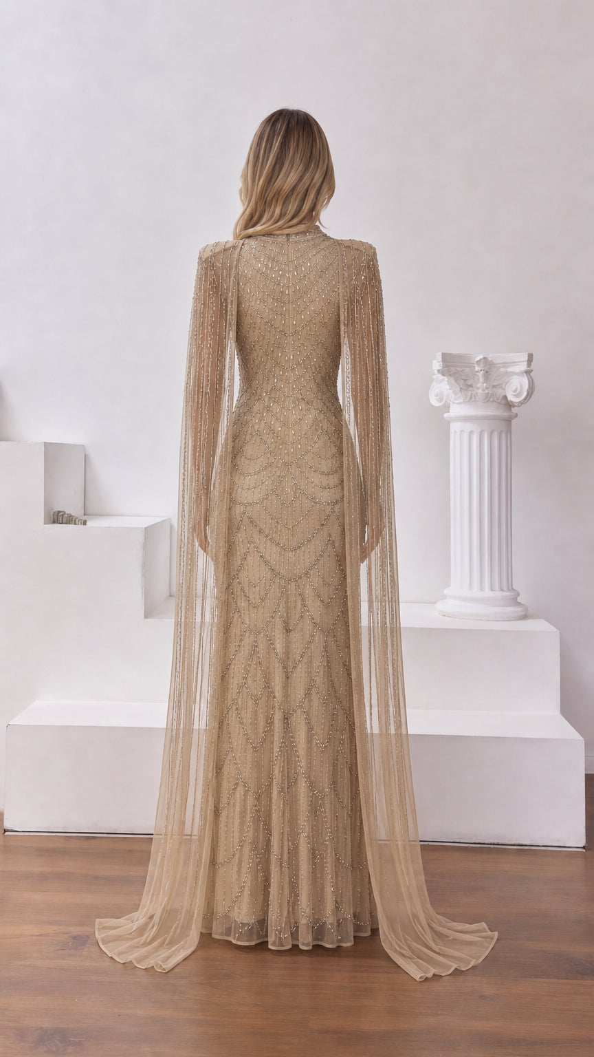 Back view of champagne embellished cape sleeve gown with fitted silhouette