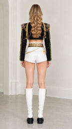 Back view of black cropped jacket with ornate shoulder chain details and white shorts