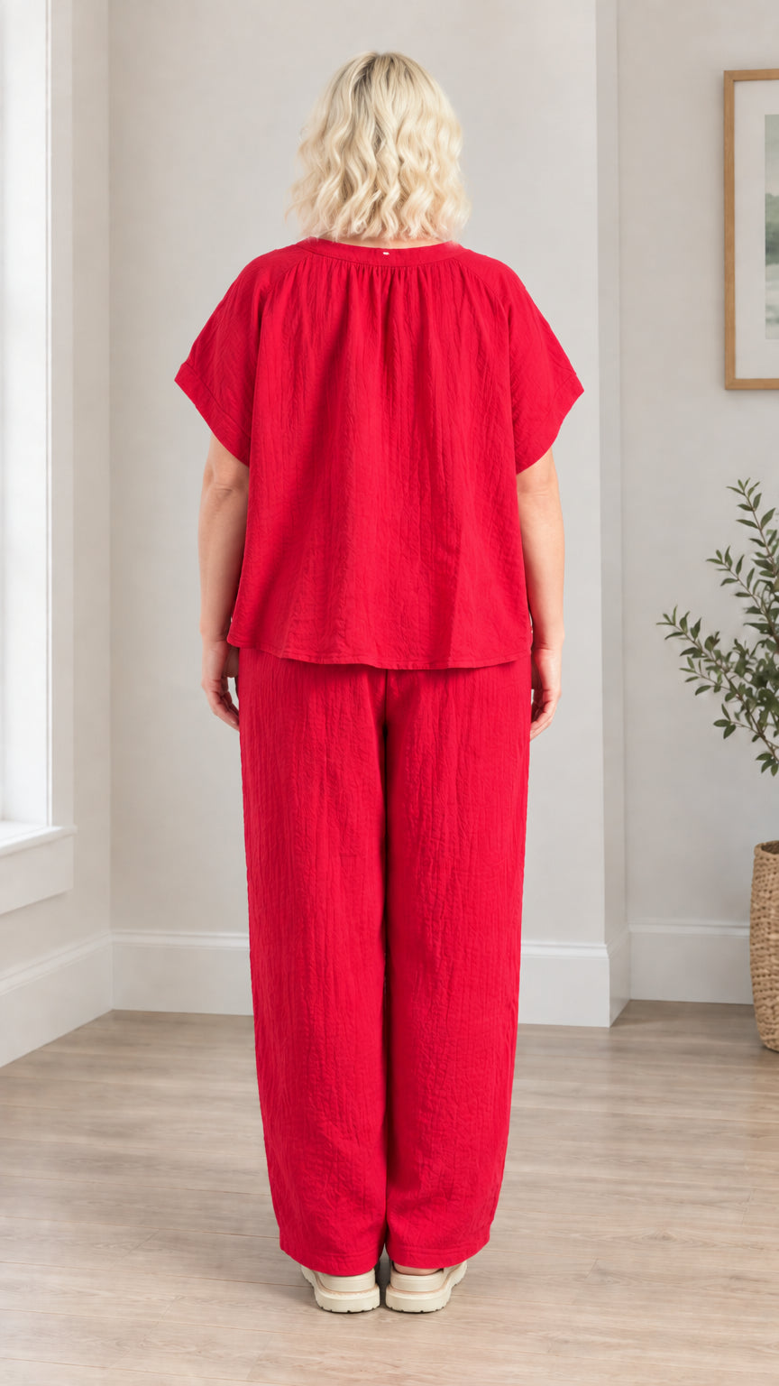 Back full-length view of model in red crinkle textured blouse and wide leg trousers set