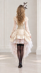 Back view of model in cream vintage corset dress showing gathered high-low hemline
