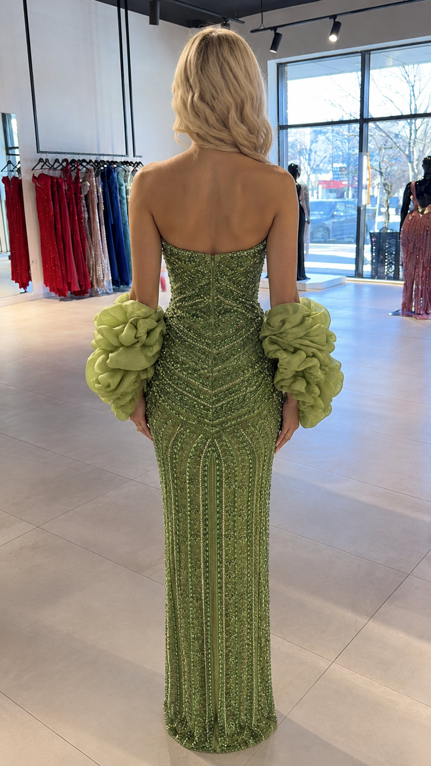Back view of model wearing green strapless column gown with dramatic ruffled cuffs