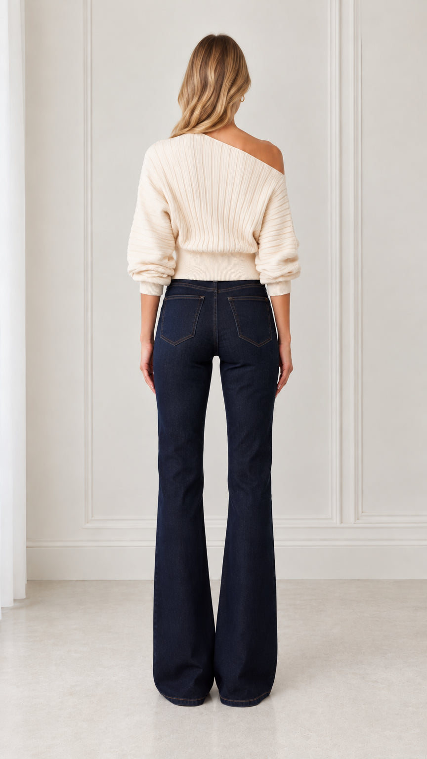 Back view of model wearing cream off-shoulder knit sweater with ribbed waistband